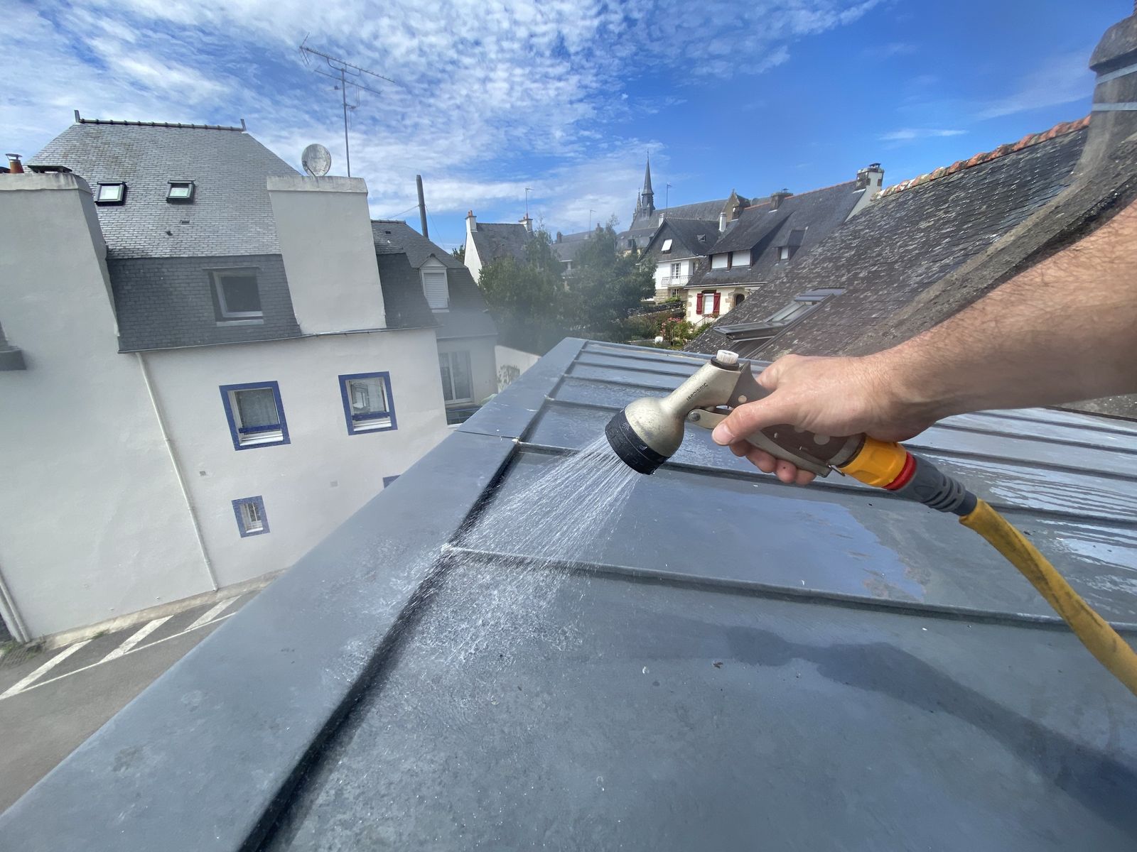Technicien testant l'étanchéité d'une toiture en zinc pour une recherche de fuite dans le Morbihan